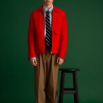 Young adult in a red jacket with a green background, studio shot.