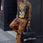 Stylish man in urban streetwear standing on Atlanta sidewalk, showcasing modern fashion.