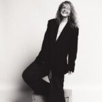 Black and white portrait of a smiling person in oversized clothing, casual and chic.