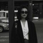 a woman standing on a sidewalk next to a pole